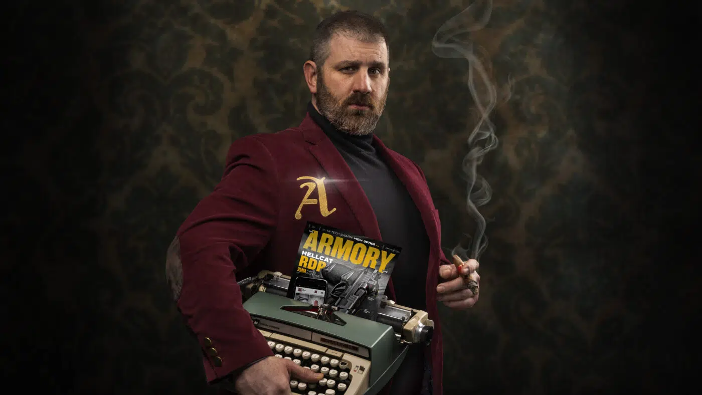 Paul Carlson in the crimson Cantius Award jacket, holding a typewriter with a copy of The Armory Life magazine and a cigar.
